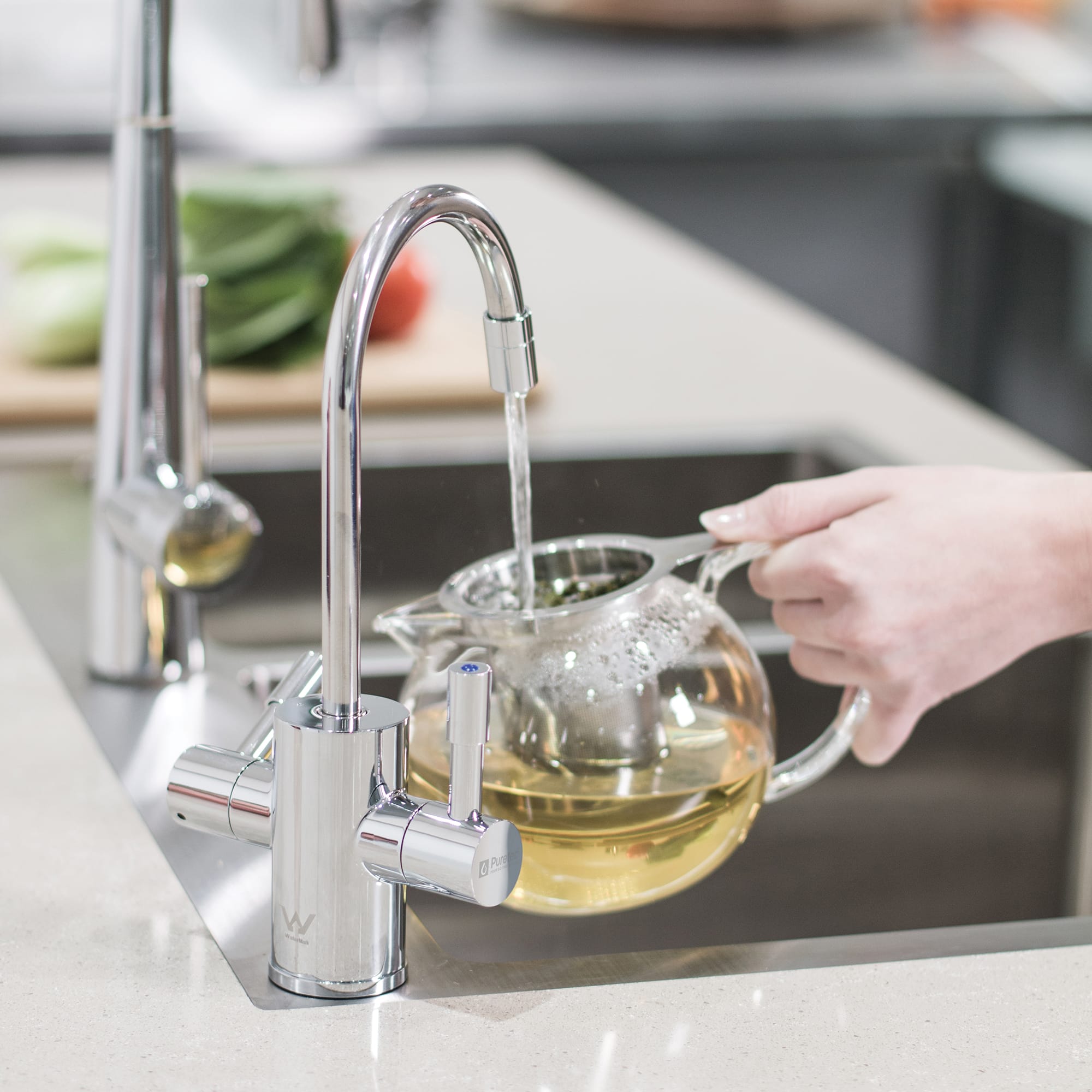 Puretec sparq-h2 boiling and chilled water tap dispensing filtered hot water into a teapot. Chrome-finished tap designed for instant boiling and chilled water in modern perth kitchens.